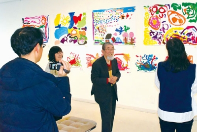 写真：来場者に子どもたちの作品を解説する工藤さん（中央）
