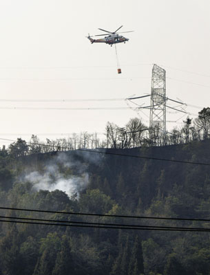 写真：岡山市南区の山林火災現場で消火活動を行うヘリコプター＝２５日午前９時９分