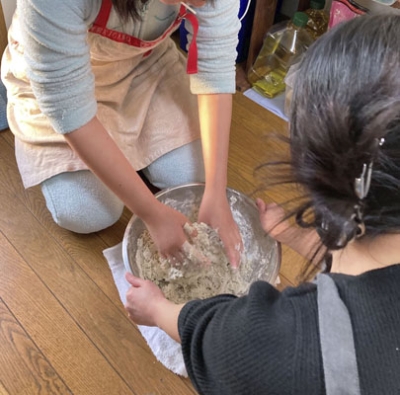 写真：佐賀県にある子どもシェルターで料理をする利用者の女性（奥）ら（佐賀子どもシェルターばるーん提供）