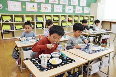 写真：初給食をおいしそうに頬張る新一年生＝海陽小