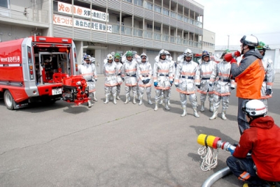 写真：小型ポンプの取り扱いなどを再確認する消防団員たち