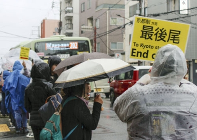 写真：雨の中、清水寺近くのバス停に並ぶ人たち＝４月、京都市