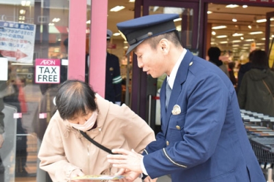 写真：買い物客に啓発物を配り、特殊詐欺に注意を呼びかける伊達署員（右）