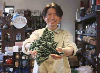 写真：群馬県の形をした「ぐんまのお皿」を手にする「三美堂」４代目の吉村聡さん＝４月、群馬県高崎市