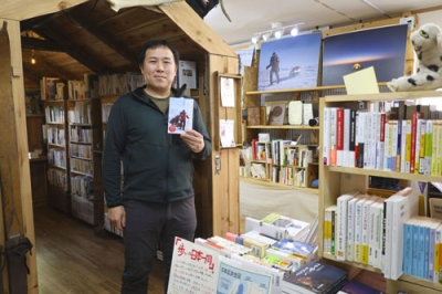 写真：自身が営む「冒険研究所書店」で本を紹介する荻田泰永さん＝３月、神奈川県大和市