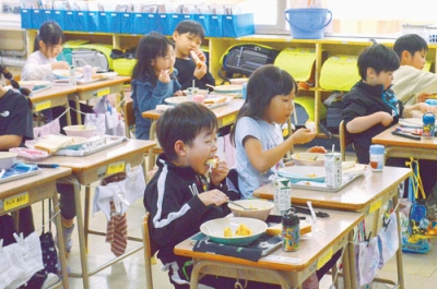 写真：おいしそうに給食を頬張る１年生