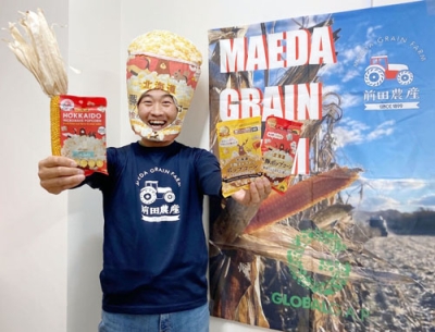 写真：商品化したポップコーンを手にポーズをとる農家の前田茂雄さん＝本別町
