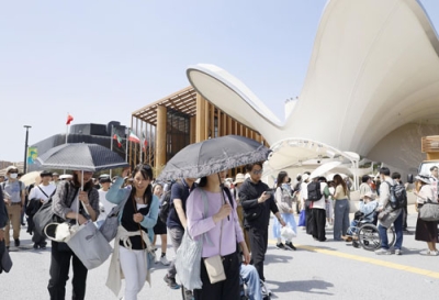 写真：開幕後初の夏日となり、日傘で暑さをしのぐ来場者＝１９日午後、大阪市此花区の夢洲