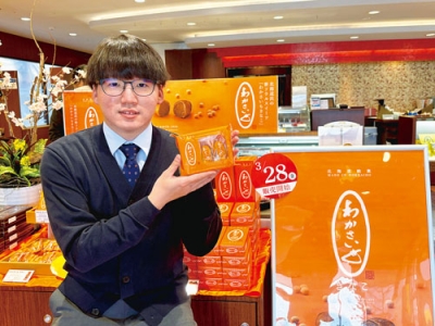 写真：「わかさいもきなこ」をＰＲする高橋店長。鮮やかなオレンジ色のパッケージが目印