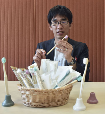 写真：コメを原料に利用した歯ブラシ「ライスクリーン」について紹介する武内和治さん＝４月、愛媛県伊予市