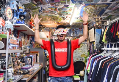 写真：名古屋市の店舗で安全バーを体に掛け、ポーズをとるジェットコースター男さん＝４月