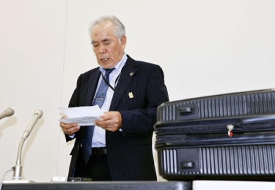 写真：報道陣の取材に応じる北海道アイヌ協会の大川勝理事長。右は遺骨が入ったスーツケース＝３日午後、新千歳空港