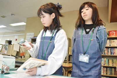 写真：本の貸し出しに挑戦する田川さん（左）と五十嵐さん