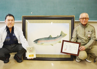 写真：最高賞を受賞した作品と髙橋さん（右）。左は小笠原会長