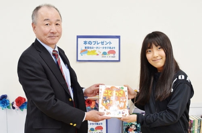 写真：斉藤幹事（左）から本を受け取る蒲原図書委員長