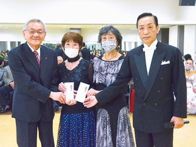 写真：ダンスパーティーの益金の一部を寄付する西村代表（右）