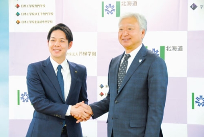 写真：包括連携協定を結び、鈴木知事と握手を交わす千葉理事長（右）