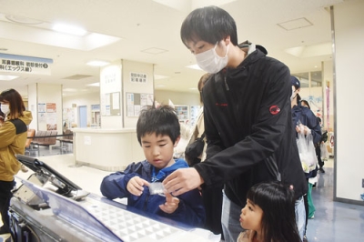 写真：薬剤師になり切り、菓子の個装に挑戦する親子