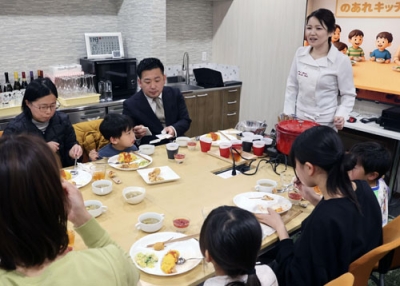 写真：子ども食堂の試食会で、食物アレルギー対応の料理を振る舞う上田まり子さん（右奥）＝３月、松江市
