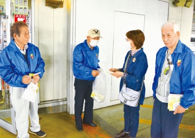 写真：アーニスの買い物客に啓発物を配る民生委員・児童委員