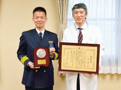写真：河野部長から渡された感謝状を手にする佐々木院長（右）