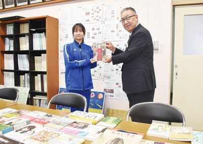 写真：贈られた書籍を川上参事（右）から受け取る小野生徒会長