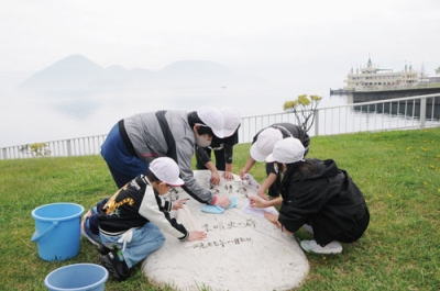 写真：湖畔沿いの彫刻清掃に励む温泉小の子どもたち