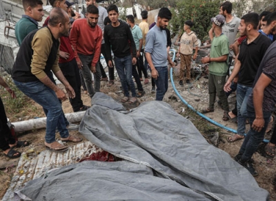 写真：パレスチナ自治区ガザで、イスラエル軍の攻撃による犠牲者の周りに集まる人々＝１８日（ゲッティ＝共同）