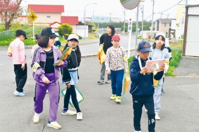 写真：学校近くの道路を歩き、気付いた箇所をタブレットで撮影する児童たち