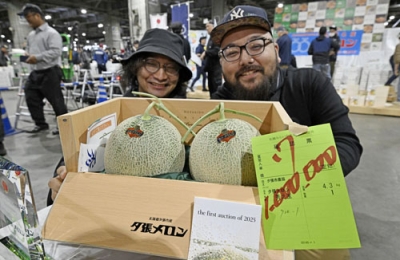 写真：初競りで２玉１００万円で落札された「夕張メロン」。後方は落札した「サンウロコ鱗商会」の柏崎慎太郎取締役（右）ら＝日午前、札幌市