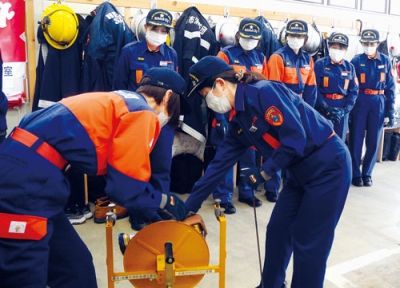 写真：訓練でホースを巻き取る女性分団員