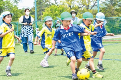 写真：元気いっぱい芝を駆け回り、ゴールを目指す園児たち