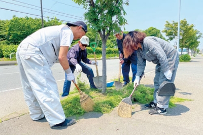 写真：植樹升の草刈りに汗を流す社員たち