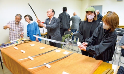 写真：堀井刀匠の解説を聞きながら日本刀に触れ、鑑賞する参加者