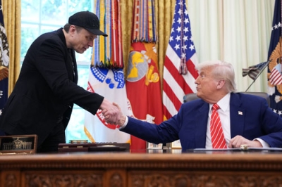 写真：３０日、米ホワイトハウスでトランプ大統領（右）と握手するイーロン・マスク氏（ゲッティ＝共同）
