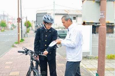 写真：自転車利用者にヘルメット着用のパンフレットを手渡す登別登別交通安全協会メンバー