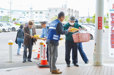 写真：買い物客に啓発物を渡す参加者たち