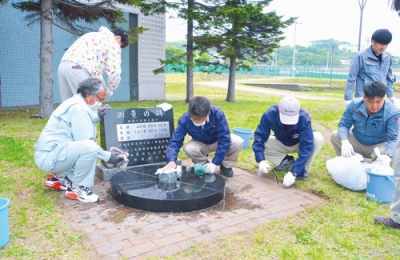 写真：「測量の碑」を丹念に手入れする参加者