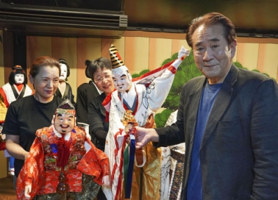 写真：「三番叟まわし」で使う阿波木偶を紹介する辻本一英さん（右）＝５月、徳島市
