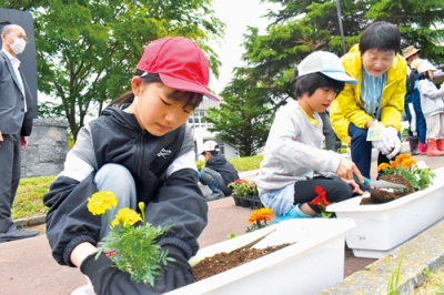 写真：優しくプランターに花苗を植える児童たち