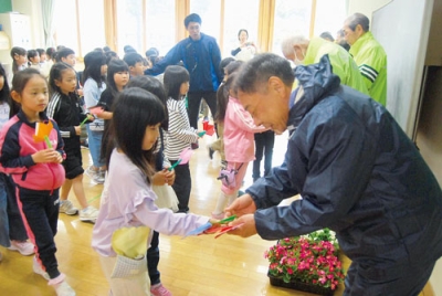 写真：会員に手作りの花をプレゼントする児童