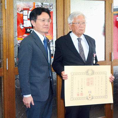 写真：叙勲の伝達を受けた大渕さん（右）と大塩町長