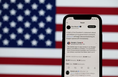 写真：トランプ米大統領とイーロン・マスク氏のソーシャルメディアでの投稿を表示したスマートフォン＝５日、米カリフォルニア州（ゲッティ＝共同）