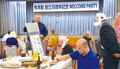 写真：記念品の掛け軸を広げて喜ぶ海外の門下生