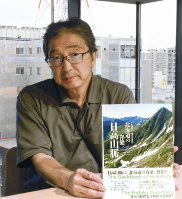 写真：書籍「北海道の脊梁　日高山脈」を手にする編著者の黒川伸一さん＝５月、札幌市