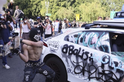写真：８日、米ロサンゼルスで車両を破壊する暴徒（共同）