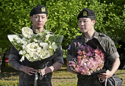 写真：１１日、韓国・漣川で、花束を手にするＢＴＳのジミンさん（右）とジョングクさん（共同）