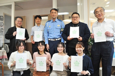 写真：交通安全アドバイザーを委嘱された室蘭まちづくり放送の沼田社長（後列左から２人目）らパーソナリティーと堀江署長（同３人目）