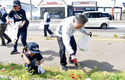 写真：草むらに落ちたごみを拾う伊達信金職員