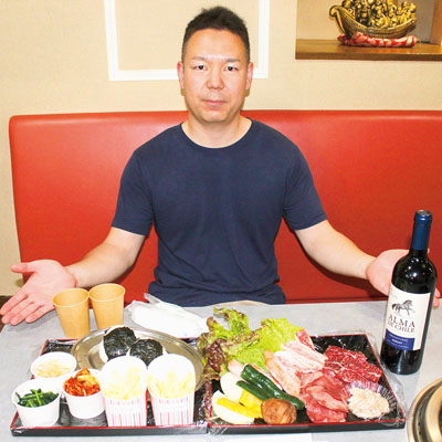 写真：笑顔でバーベキューセットを紹介する清水佑哉店長